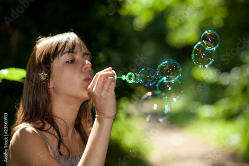girl blowing bubble soap in nature