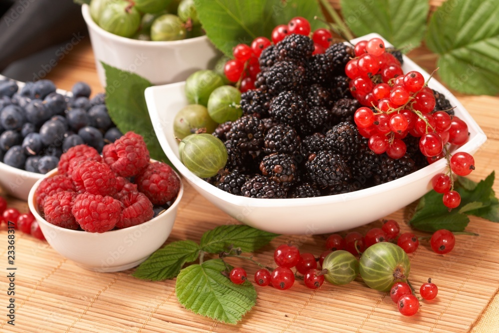 Berries in plates, on a table, among green leaves Berries in plates, on a table, among green leaves