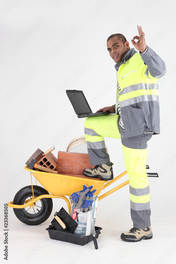 Ouvrier satisfait devant un ordinateur portable Ouvrier satisfait devant un ordinateur portable