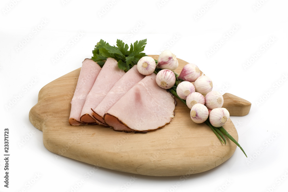 slices of ham on wooden plate and garlic