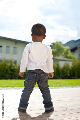 Young afro american baby playing around in the garden.