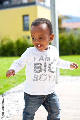 Young afro american baby playing around in the garden.