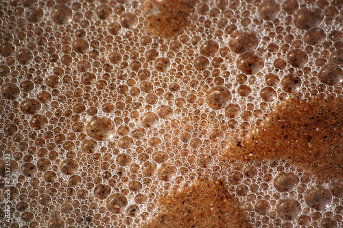 Texture of wet sand and ocean bubbles