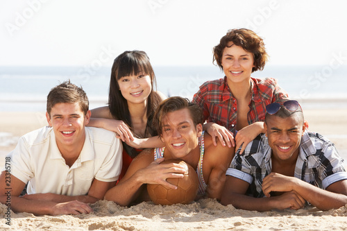 Group Of Friends Relaxing On Beach With Football Together
