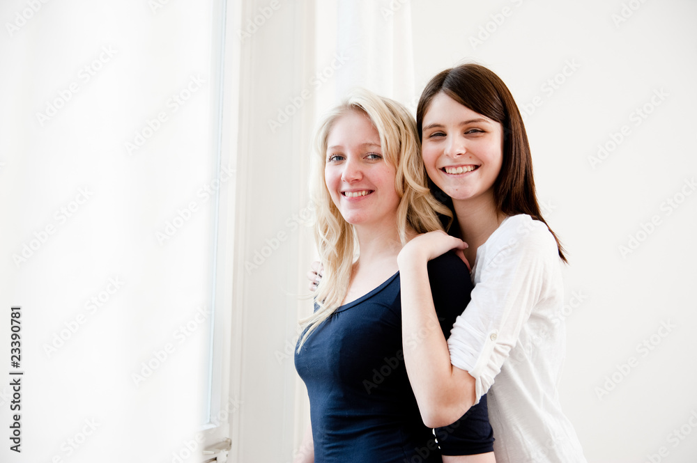 zwei freundinnen umarmen sich in wohnung