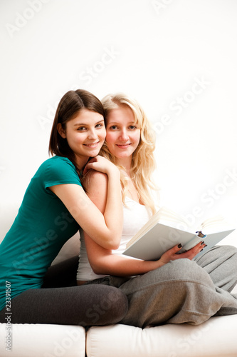 zwei freundinnen entspannen mit buch auf sofa