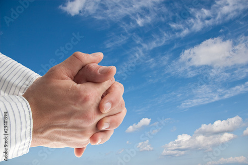 praying hand in front of a blue sky