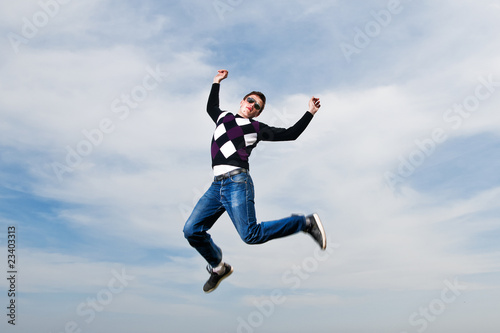 young man in the eyeglasses jumping in clouds