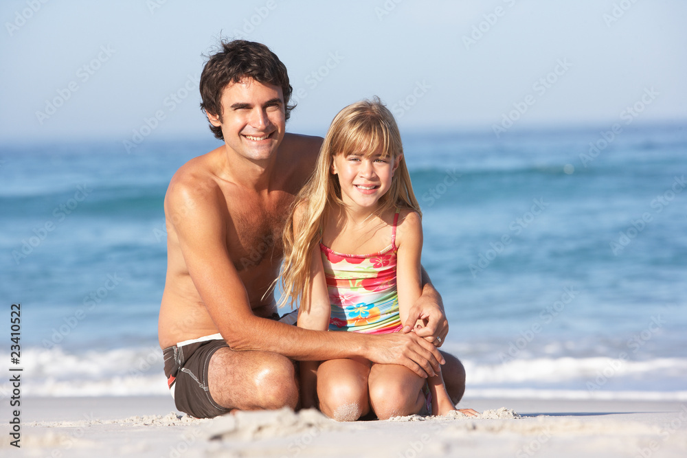 Father And Daughter Wearing Swimwear Sitting On Sandy Beach Father And Daughter Wearing Swimwear Sitting On Sandy Beach