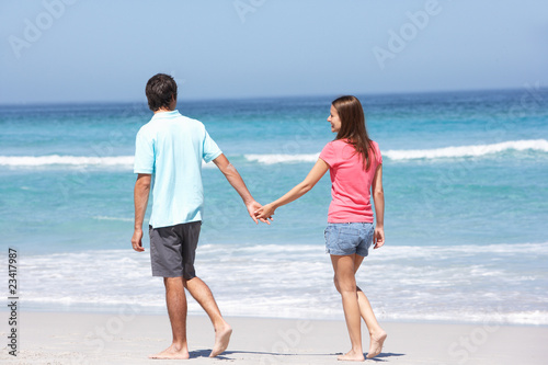 Couple On Holiday Walking Along Sandy Beach