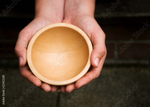 White hands holding a wooden begging bowl photo