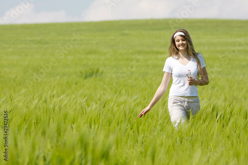 young happy girl walking in green field