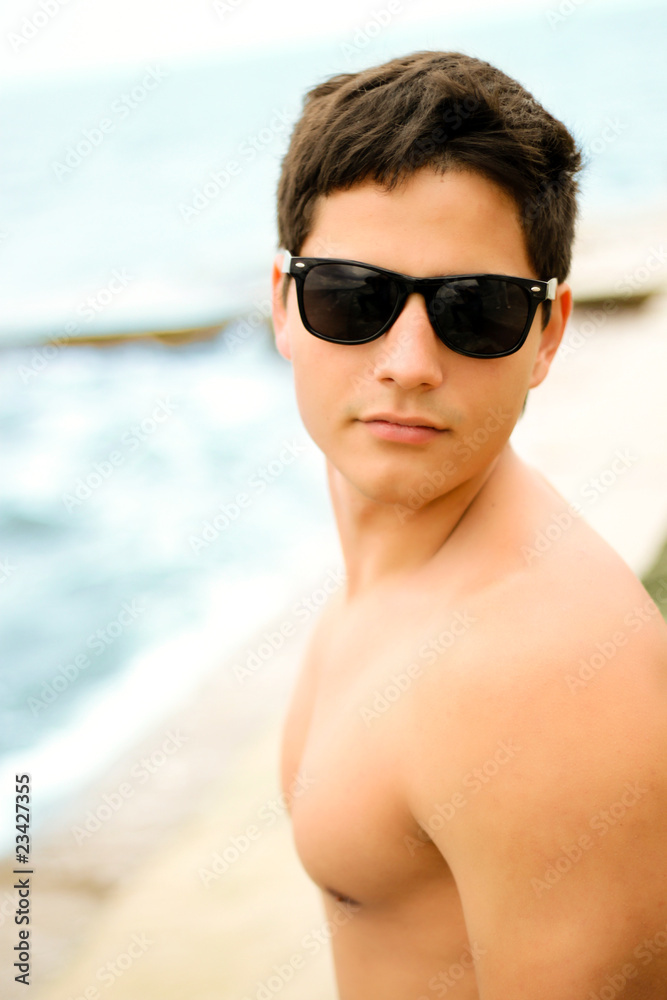 Young muscular man in sunglasses on the seashore Young muscular man in sunglasses on the seashore