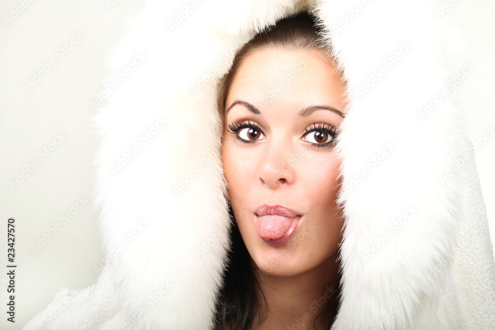 Beautiful brunette in white fur showing tongue on white Beautiful brunette in white fur showing tongue on white