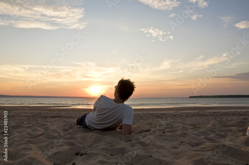 Young man lying on the beach back to the camera