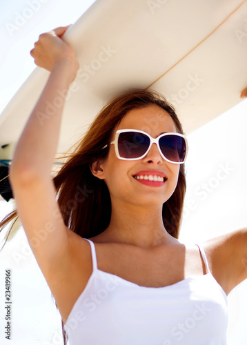 Smiling beach woman holding surfboard on her head