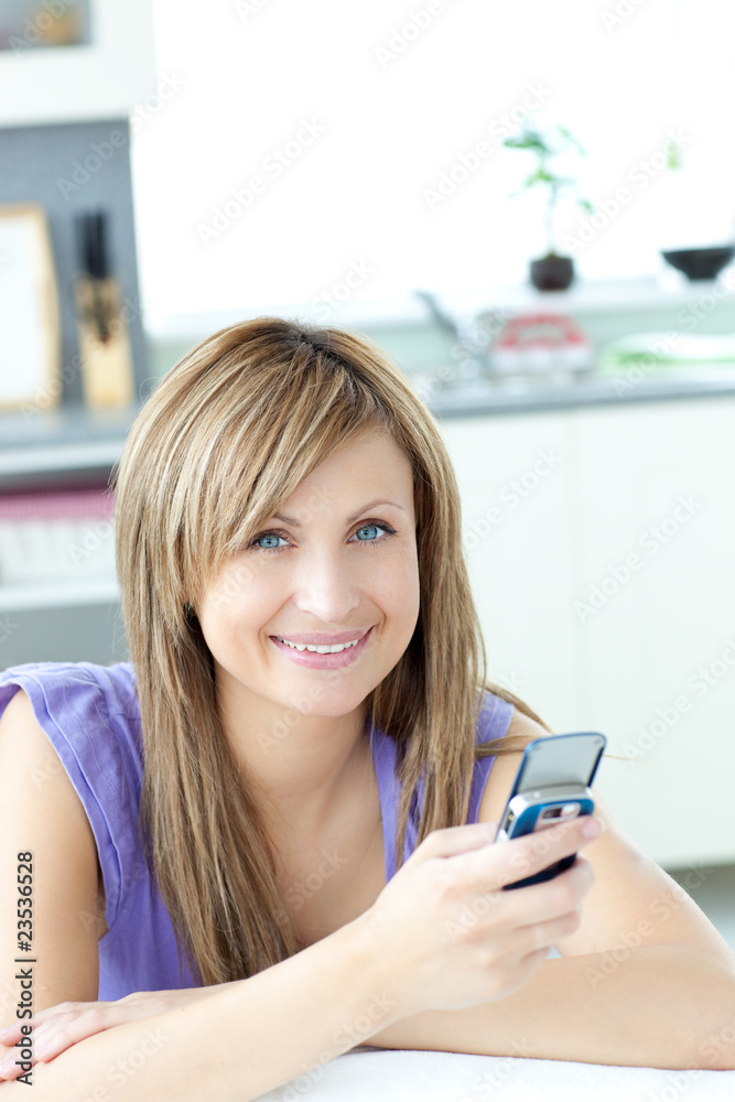 Teen woman sending a text in the kitchen Teen woman sending a text in the kitchen