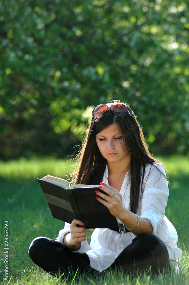 College student reads book in park