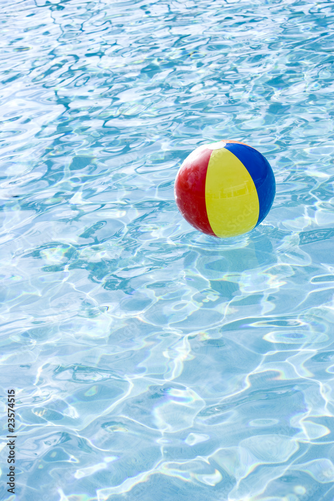 Beach ball floating on surface of swimming pool