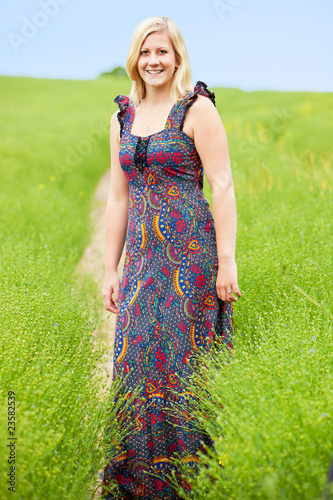 Beautiful young blond standing in field wearing a long paisley p