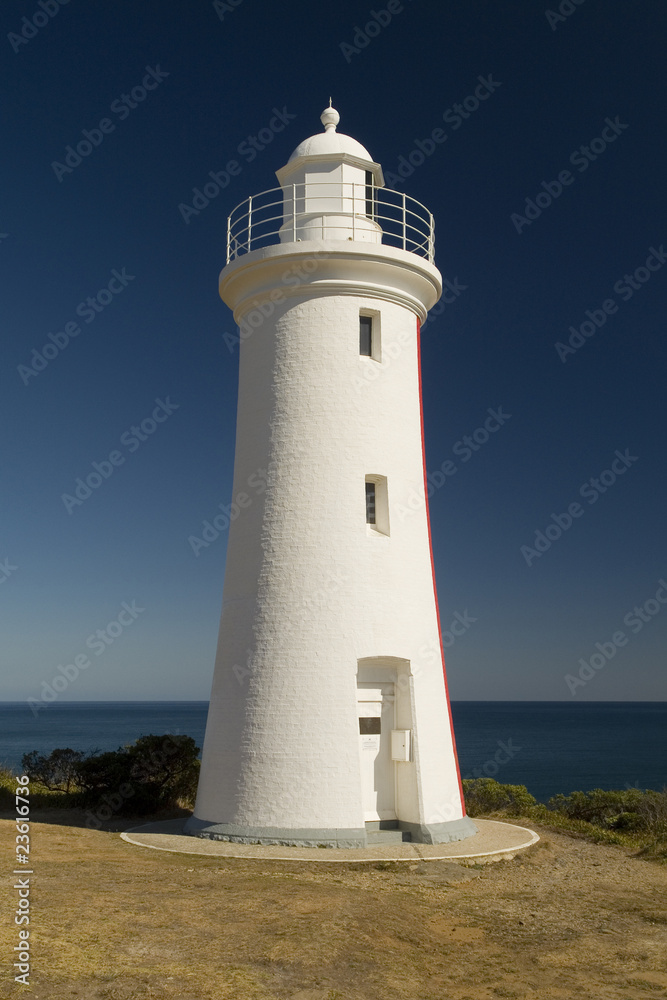 White Washed Lighthouse Against Blue Sky