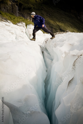 Man crosses a deep crevasse on Fox Glacier, New Zealand