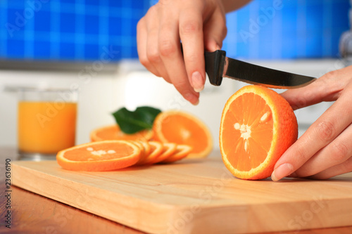 Female chopping juicy orange on the kitchen.