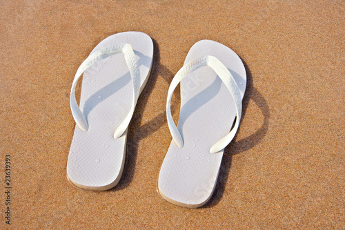 white flip flops on sand beach