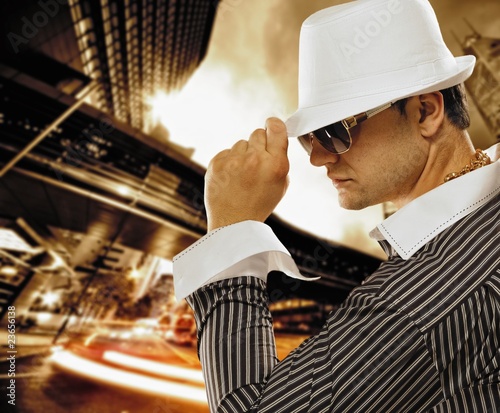 Fotografie Stylish man in a hat in front of night city