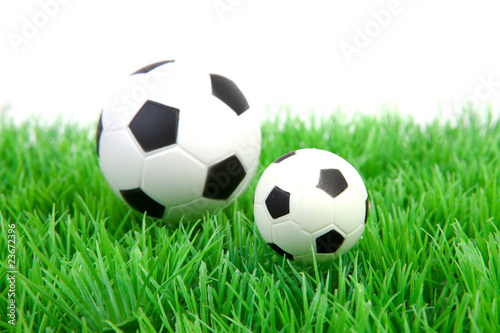 Two soccer balls on grass over white background