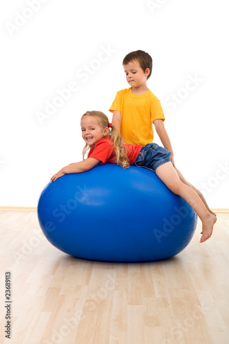 Kids doing exercises on large rubber ball