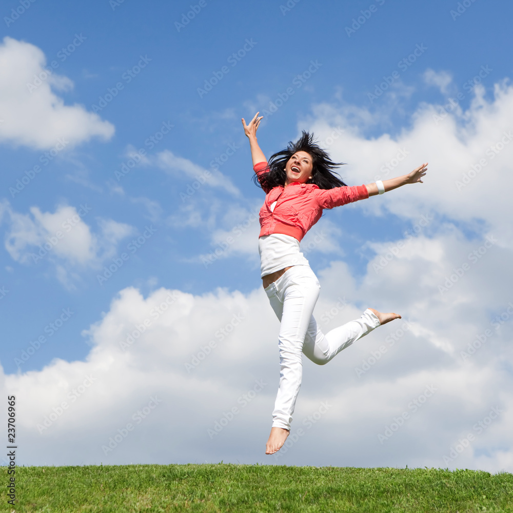 pretty young woman jumping on green grass