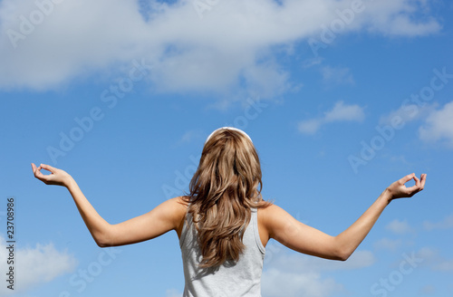 Peaceful young woman meditating against a blue sky