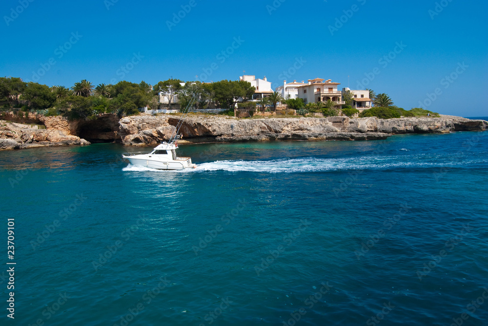 Motor boat in front of the rocky coast, Majorca, Spain