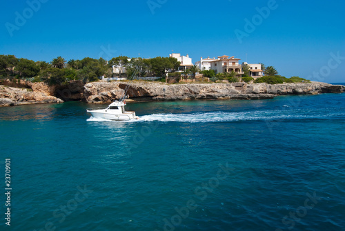 Motor boat in front of the rocky coast, Majorca, Spain
