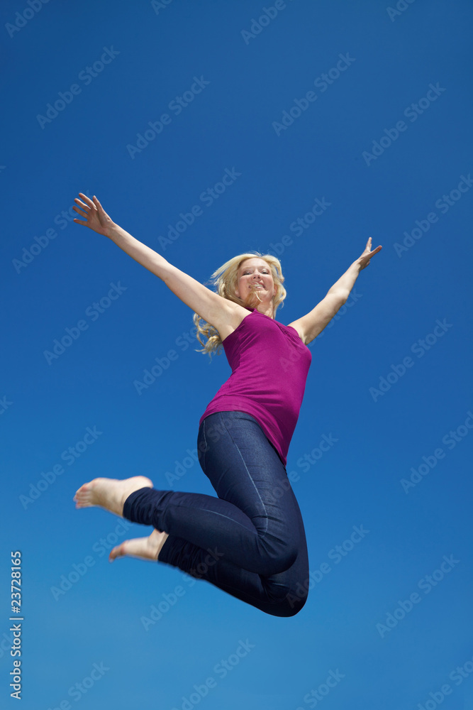Blondine springt vor blauem Himmel Blondine springt vor blauem Himmel