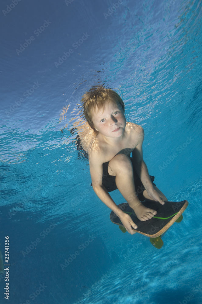 little boy pretending to skate board underwater