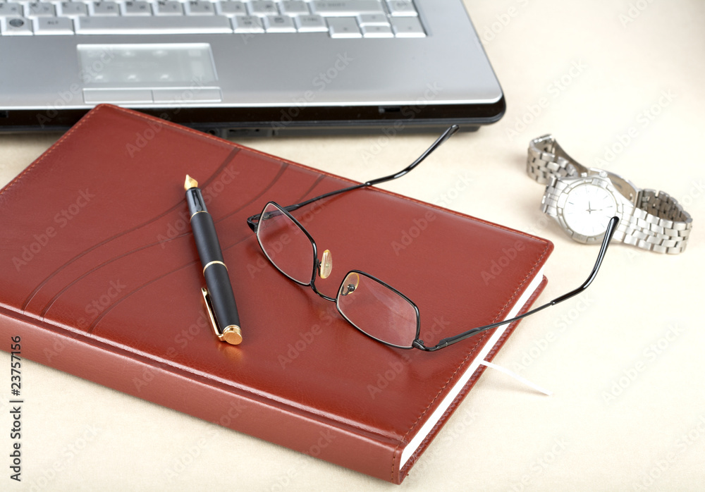 The laptop an organizer a pen and clock The laptop an organizer a pen and clock