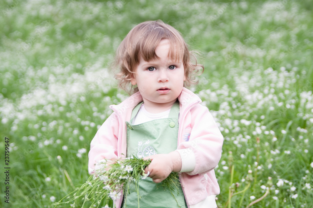 Little beautiful girl with bunch of flowers at green spring mea