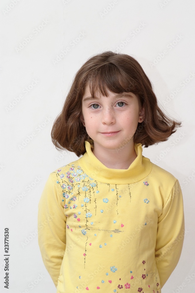 Serious cute little girl stands against the wall Serious cute little girl stands against the wall