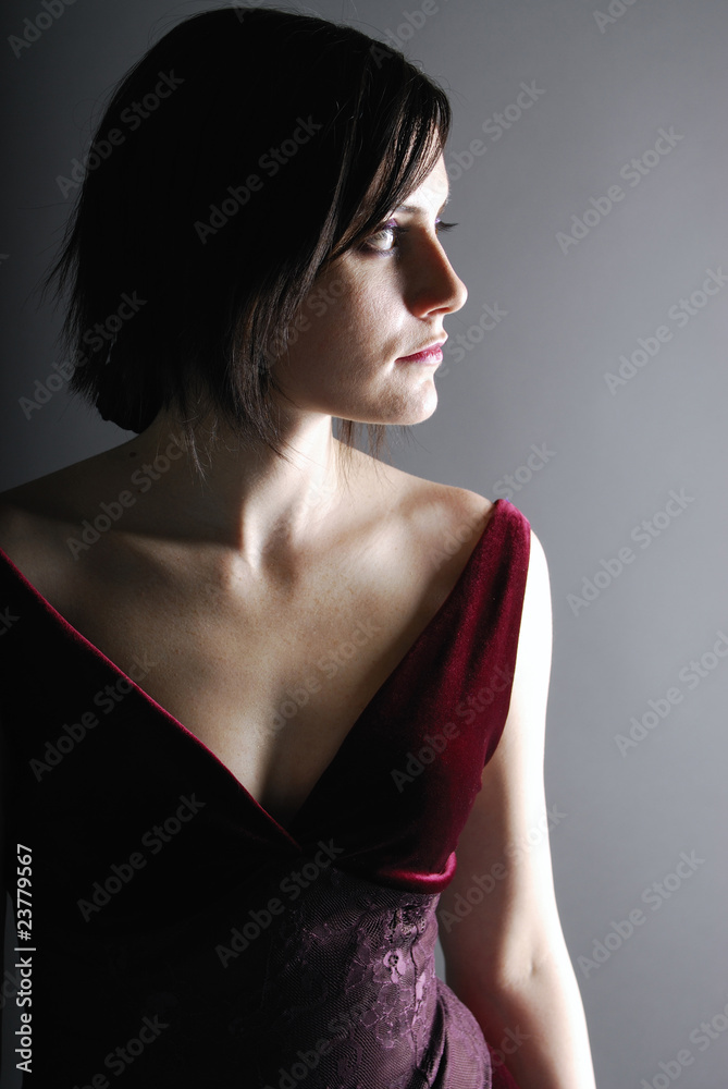 Naklejka premium Woman in a classic pose in burgundy dress