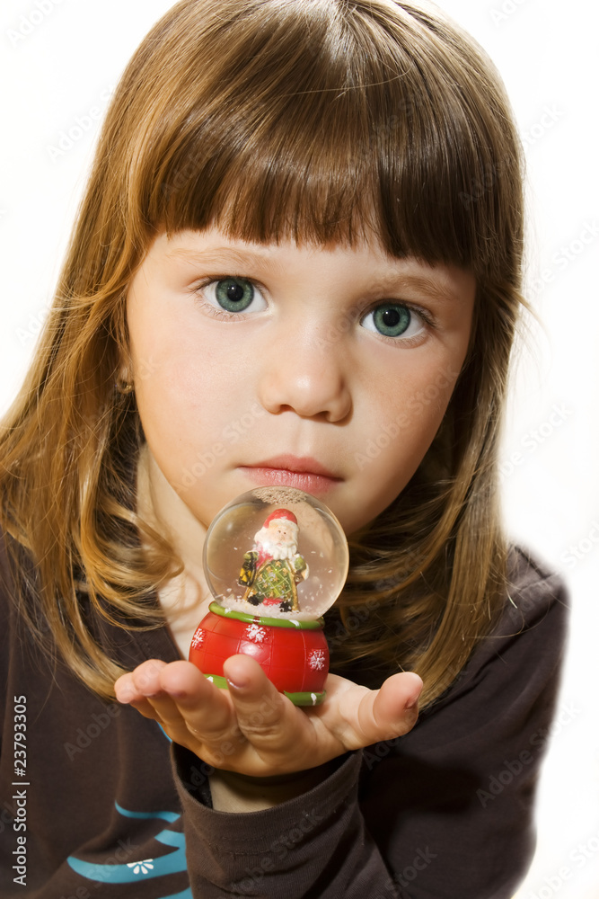 Naklejka premium Little girl hold Santa claus figurine on a glass snowing ball