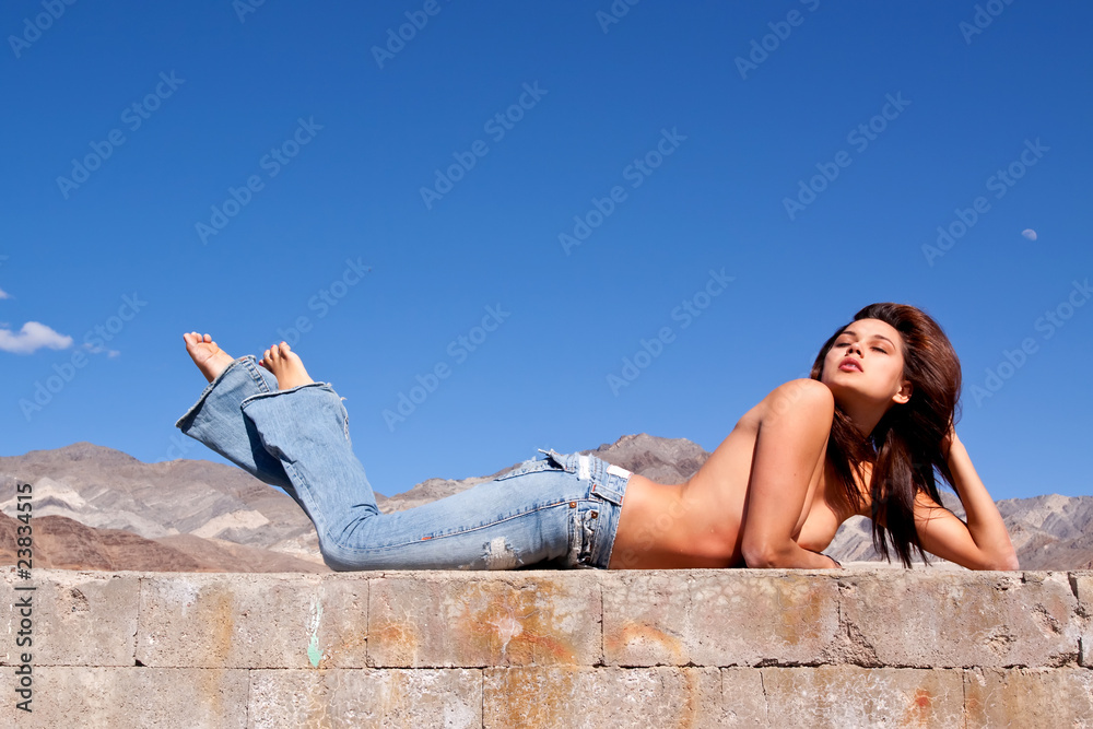 Beautiful brunette girl laying on a concrete wall