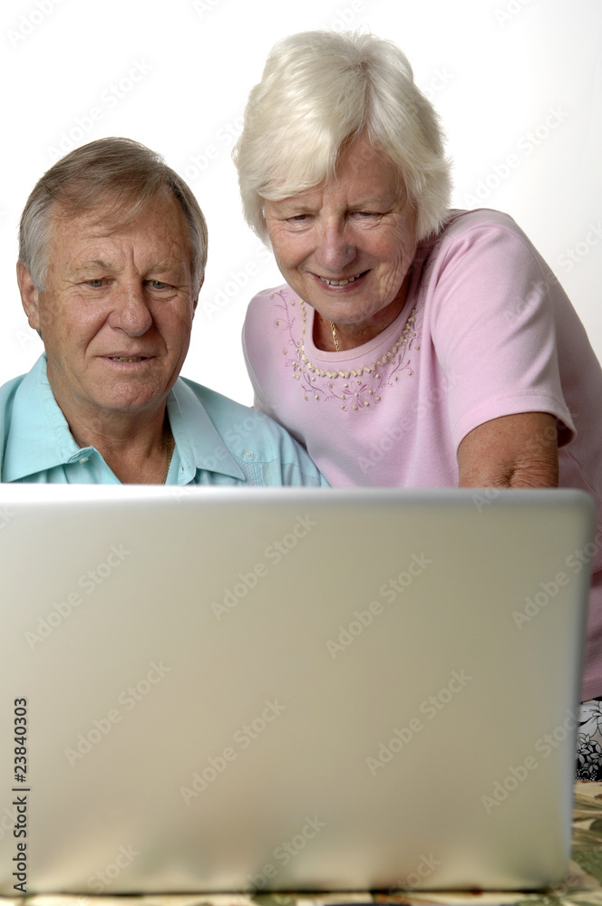 Senior couple browses Internet on their laptop.