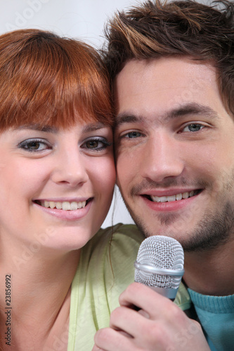 Canvastavla Portrait of a smiling couple singing in a microphone