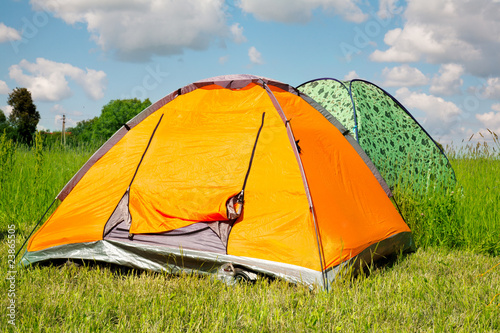 Bright tourist tent on green grass against the blue sky.