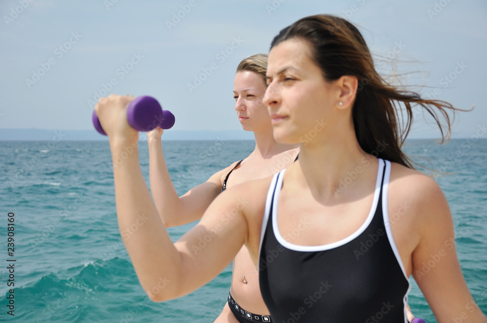 Young students lifting weights on the beach Young students lifting weights on the beach