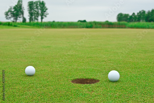 Two golf balls near the hole
