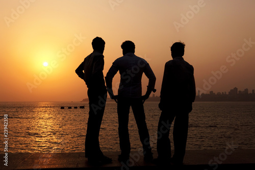 3 Indian guys watch the sunset over Mumbai