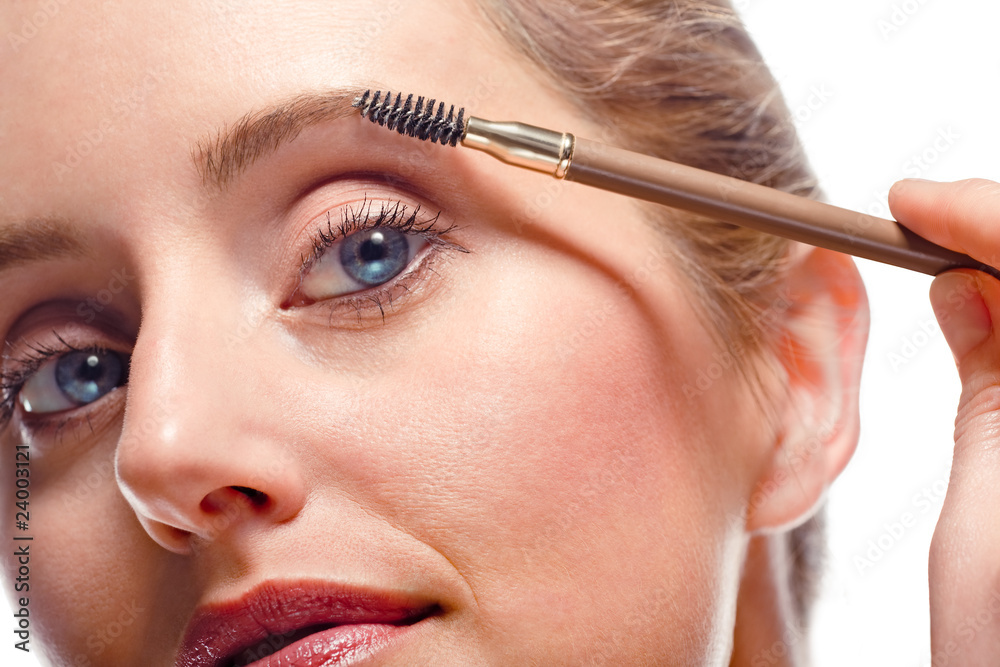 Woman applying make-up using eyebrow brush